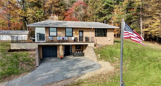 view of front facade with brick siding, a front yard, a chimney, driveway, and an attached garage