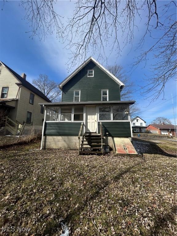 rear view of house with entry steps and a sunroom