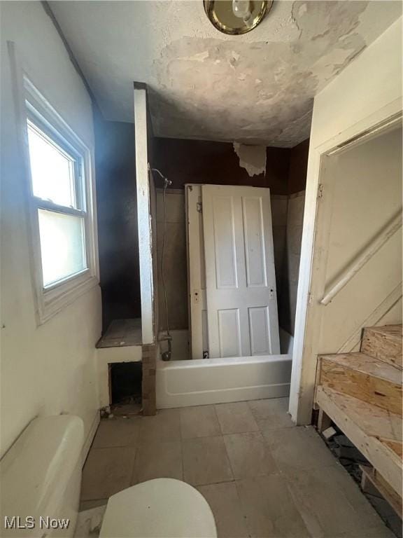 bathroom featuring toilet, bathing tub / shower combination, and tile patterned flooring