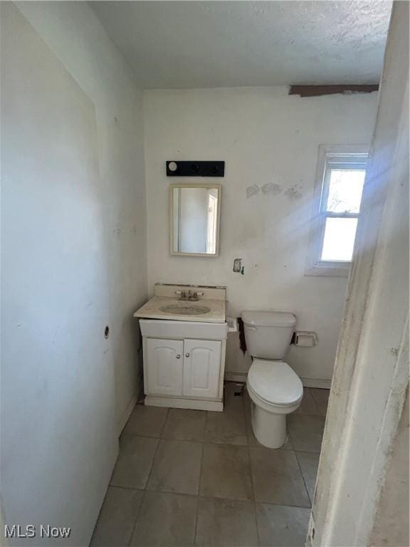 half bathroom with tile patterned flooring, toilet, and vanity