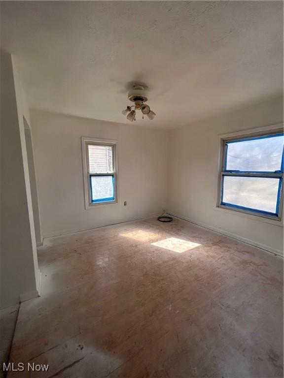 unfurnished room with baseboards and plenty of natural light