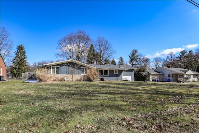 single story home featuring a chimney, a garage, and a front yard