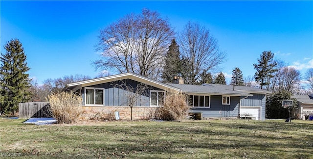 view of front of property featuring stone siding, board and batten siding, a chimney, and a front yard