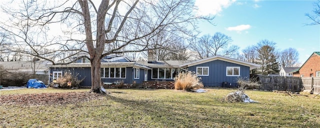 rear view of property with a yard, fence, and a chimney