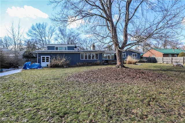 view of front facade featuring a front yard, fence, and a chimney