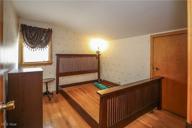 bedroom featuring wallpapered walls and wood finished floors