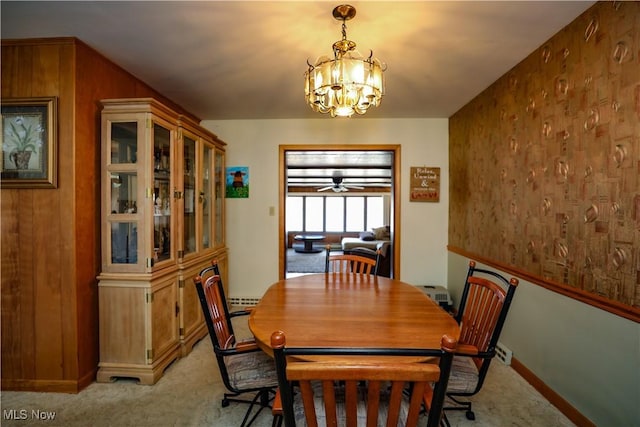 dining space featuring light colored carpet, an inviting chandelier, and wood walls