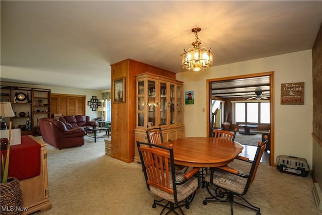 dining area with light carpet and a notable chandelier