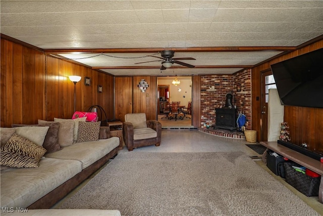 carpeted living area with ceiling fan, wood walls, and a wood stove