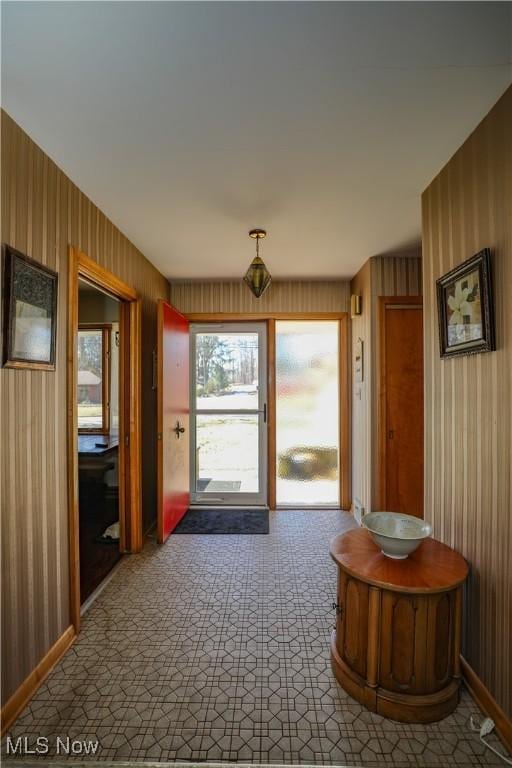 doorway to outside featuring wood walls and baseboards