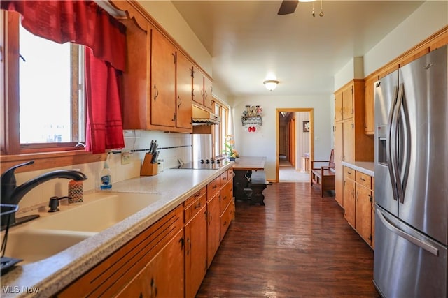 kitchen with a sink, light countertops, stainless steel refrigerator with ice dispenser, black electric stovetop, and tasteful backsplash