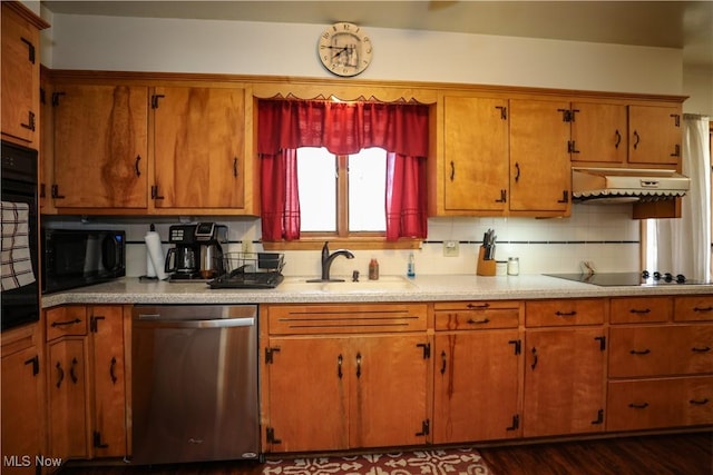 kitchen featuring black appliances, under cabinet range hood, a sink, light countertops, and decorative backsplash