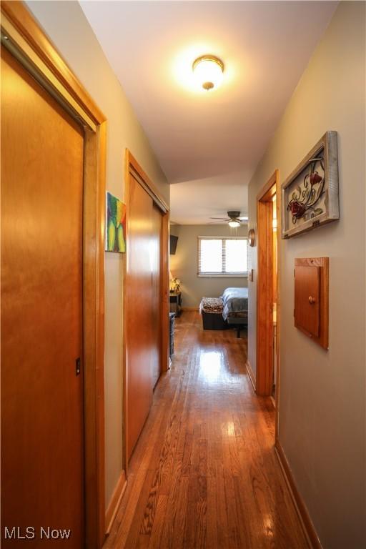 corridor with wood finished floors and baseboards