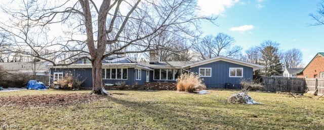 back of property featuring a lawn and fence