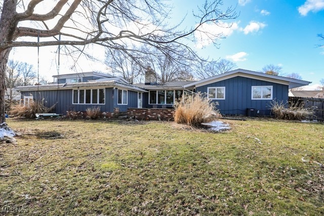 exterior space with fence, a lawn, board and batten siding, and a chimney