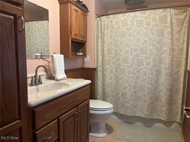 bathroom featuring vanity, a shower with curtain, a wainscoted wall, tile patterned flooring, and toilet