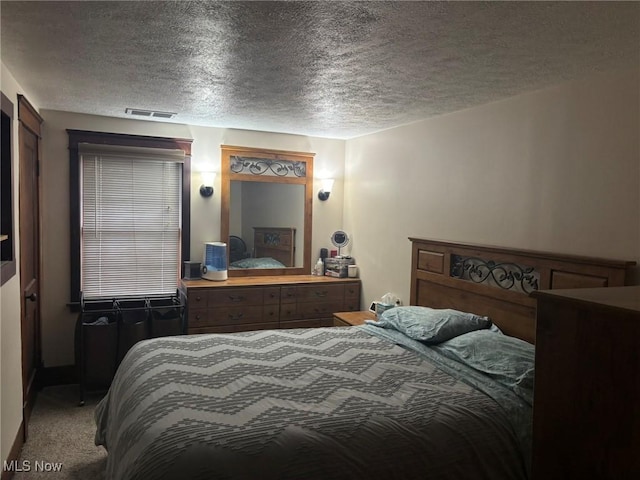 bedroom with visible vents, carpet, and a textured ceiling