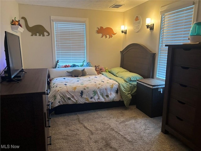 bedroom featuring carpet flooring, a textured ceiling, and visible vents