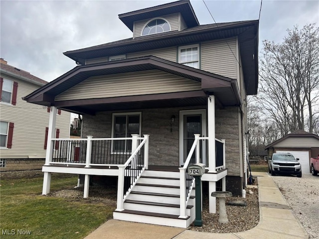 traditional style home with covered porch, a detached garage, and an outdoor structure