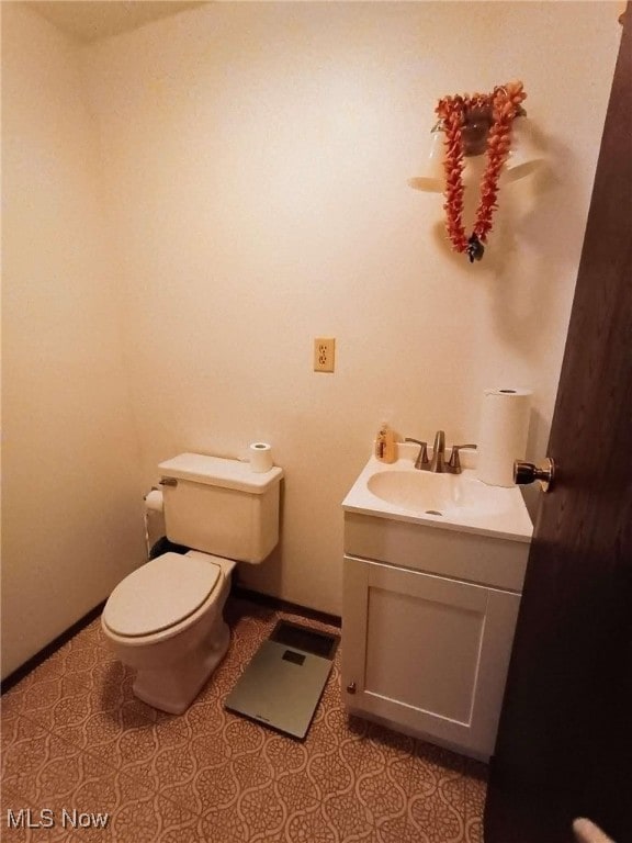 half bathroom featuring tile patterned flooring, toilet, vanity, and baseboards