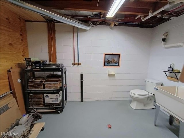 bathroom with finished concrete floors, toilet, and concrete block wall