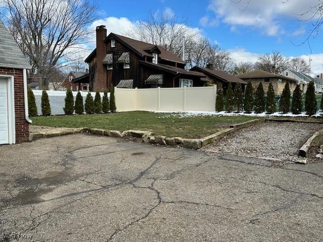 view of property exterior with a yard, a garage, a chimney, and fence