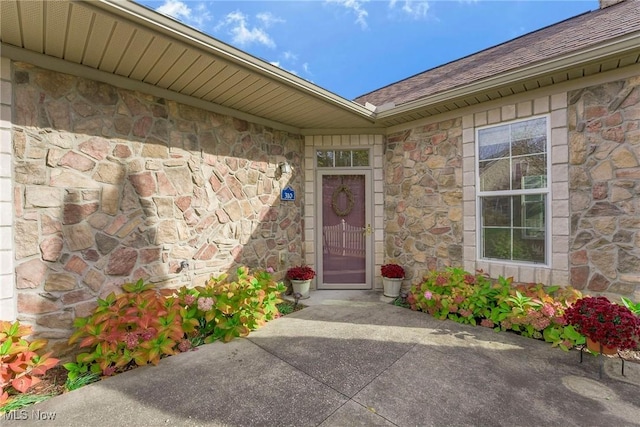 property entrance featuring stone siding and a shingled roof