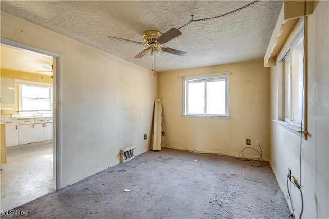 spare room with a sink, visible vents, a textured ceiling, and a ceiling fan