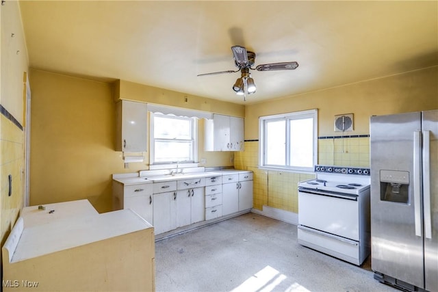 kitchen featuring white range with electric cooktop, stainless steel fridge with ice dispenser, light countertops, white cabinets, and tile walls