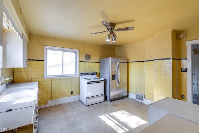 kitchen with visible vents, a wainscoted wall, stainless steel refrigerator with ice dispenser, white range with electric stovetop, and tile walls