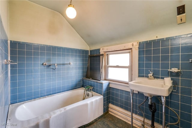 full bath featuring tile walls, a tub, lofted ceiling, and wainscoting