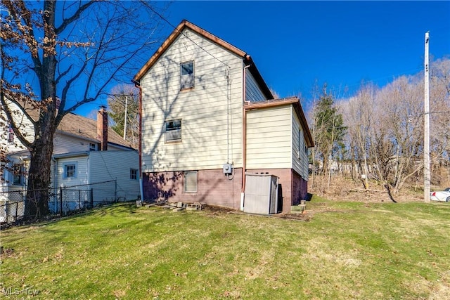 back of house with a lawn and fence