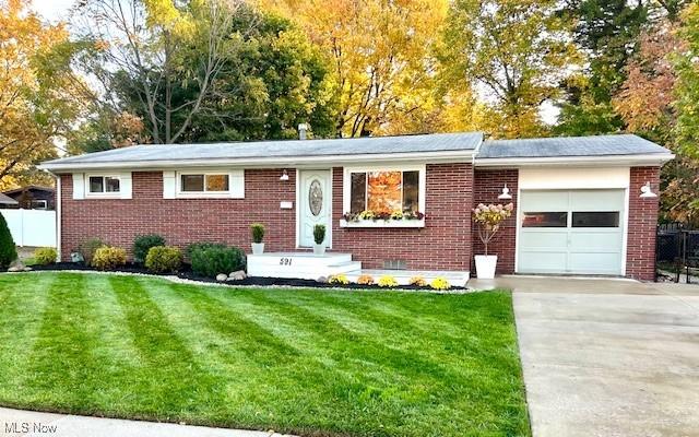 single story home featuring a front yard, fence, driveway, a garage, and brick siding