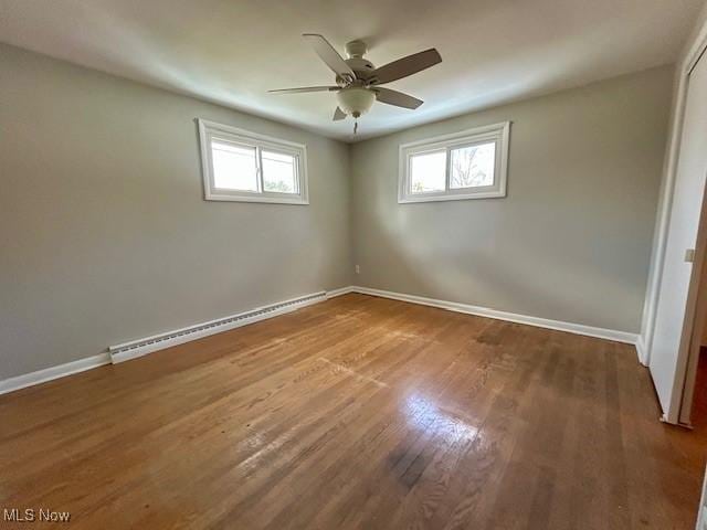 spare room featuring a wealth of natural light, wood finished floors, baseboards, and a baseboard radiator