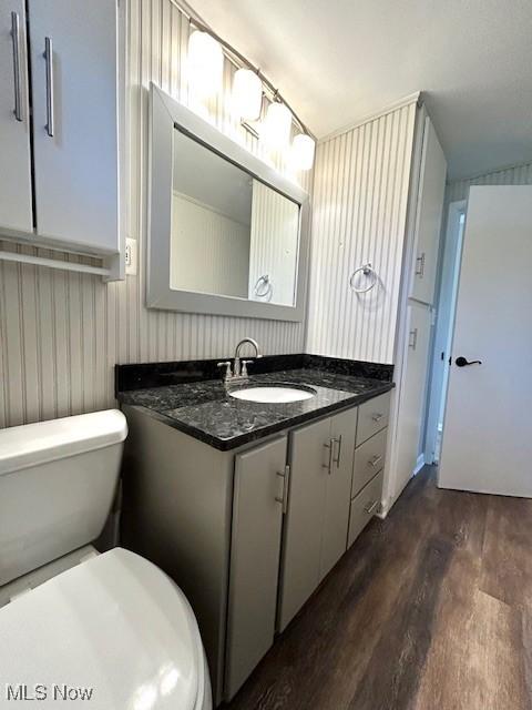 bathroom with toilet, vanity, and wood finished floors