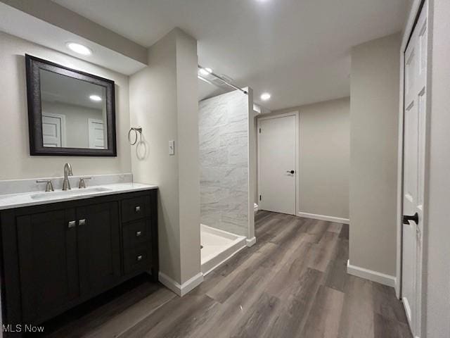 full bath featuring vanity, wood finished floors, baseboards, recessed lighting, and a shower stall