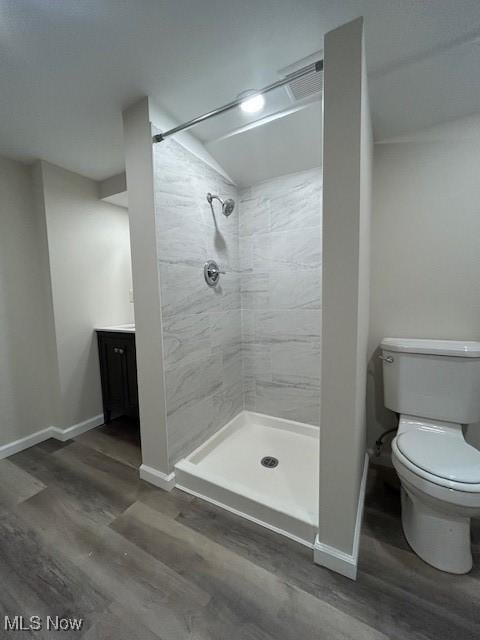 full bathroom with baseboards, toilet, wood finished floors, and a shower stall