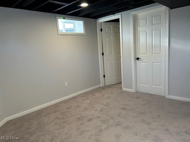 below grade area with baseboards and light carpet