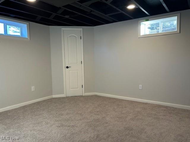 below grade area featuring carpet flooring, a healthy amount of sunlight, and baseboards