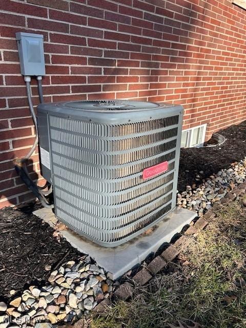 details featuring cooling unit and brick siding