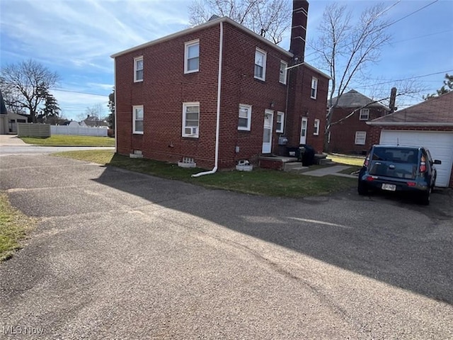 view of side of home with an outbuilding, brick siding, and a chimney