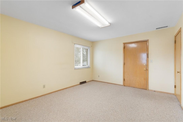 unfurnished room with visible vents, baseboards, and light colored carpet