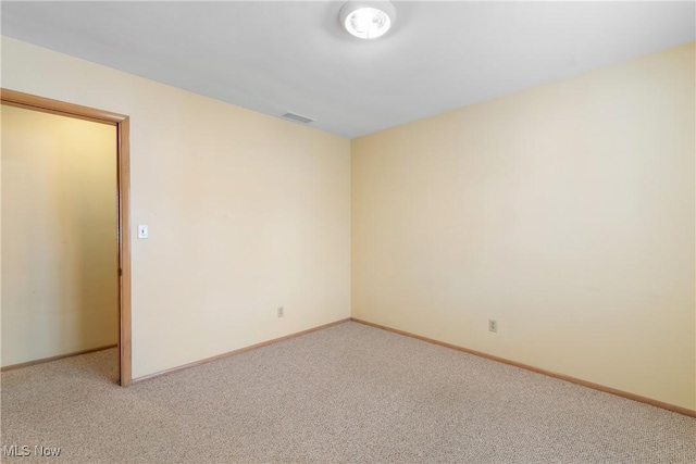 spare room featuring visible vents, light carpet, and baseboards