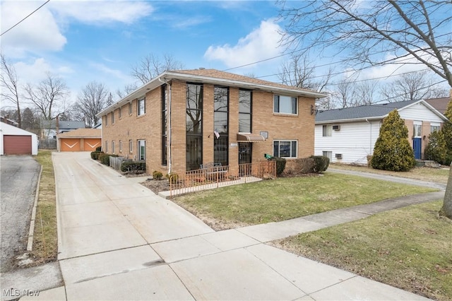 view of front of home featuring brick siding, a detached garage, and a front yard