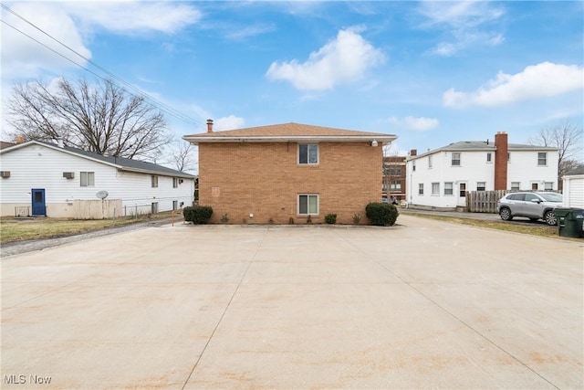 view of side of home with brick siding and fence