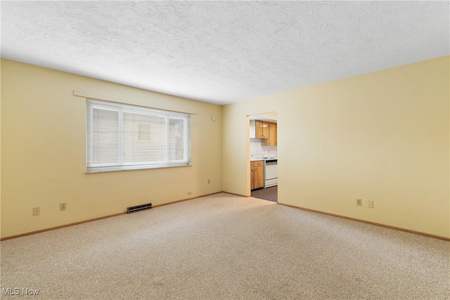 spare room featuring carpet flooring, baseboards, visible vents, and a textured ceiling