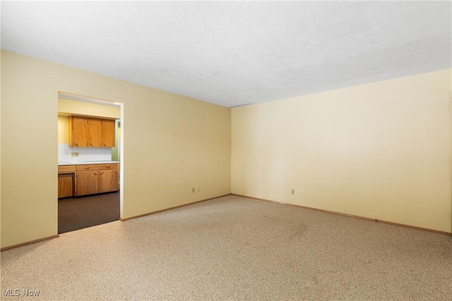 carpeted spare room with baseboards and a textured ceiling