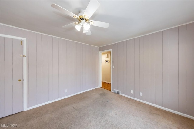 empty room with visible vents, baseboards, a ceiling fan, and carpet flooring