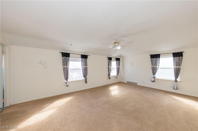 carpeted empty room featuring visible vents and a ceiling fan