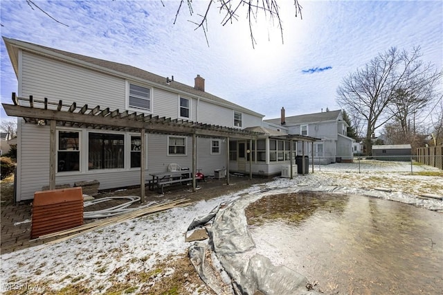 rear view of property with a chimney, a pergola, a sunroom, and fence